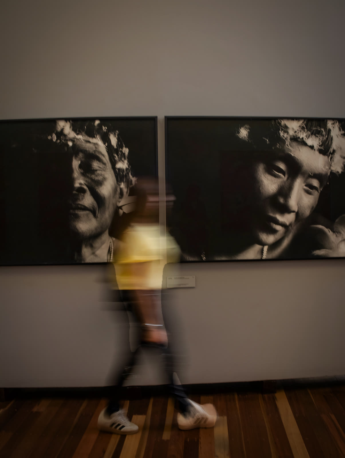 Visitante em movimento diante de retratos em galeria de Inhotim
